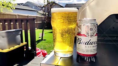 Slow motion beer pint with a Budweiser can beer on the side of a BBQ grill