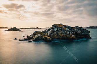 Calm sea with isles of rocks in beautiful golden dusk light after sunset