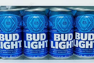 Cans of Bud Light Beer lined up on a shelf in a refrigerator.