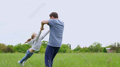 Dad playing with daughter in the field, tosses and circles. fun with the family outdoors.