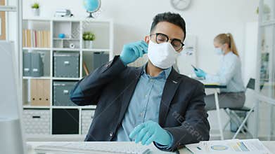 Slow motion of Arab man working with computer in office taking off face mask feeling discomfort