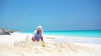 Young father and little kids making sand castle at tropical beach