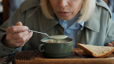 A woman eating delicious soup in a restaurant. Professionally prepared hot dish.