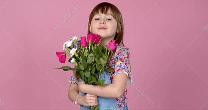 Sweet adorable young little girl holding bunch of fresh spring flowers. Wearing dungarees