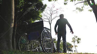 Asian old man standing up from wheel chair stretching arms