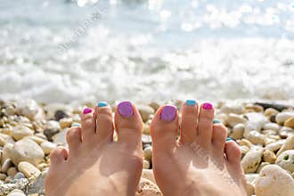 Funny woman feet with multi-colored pedicure on summer beach background. Vibrant outdoors horizontal inspirational motivational