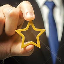 Man holds a golden star in his hand. Symbol of success and excellence. Good reputation, prestige, high recognition. Status, rating