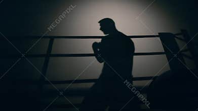 Shadow of a man boxing on a ring in the dark