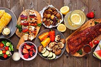 Summer BBQ or picnic food table scene, top down view over a dark wood background