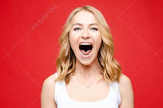 Portrait of young beautiful caucasian woman with medium blonde wavy hair and nude makeup in white t-shirt screaming in