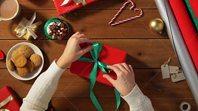 Hands packing christmas gift and tying green bow