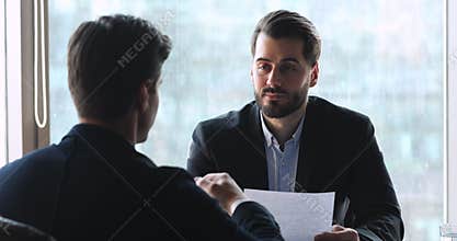Smart businessman discussing contract details with partner in office.