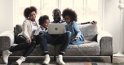 African ethnicity couple listening to music on laptop with kids.