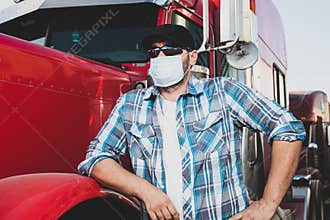 Covid-19 impacting the transportation  industry concept with truck driver wearing safety face mask next to big rig. Confident truc