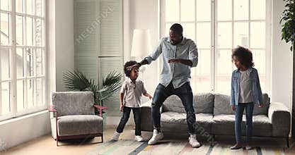 Smiling african ethnicity father showing dancing moves to children.