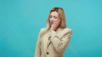 Frustrated adult woman in business suit touching her cheek, feeling acute pain in her tooth, upset with gum disease