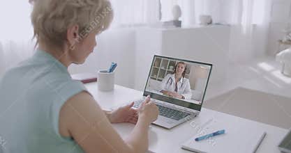 Female patient is calling at hospital and talking with woman doctor by video conference on laptop, staying home