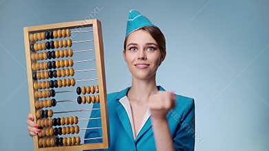 Attractive joyful stewardess is holding an abacus. Low-cost airline.