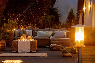 Summer night in the garden with trendy furniture, lights, lanterns and candles