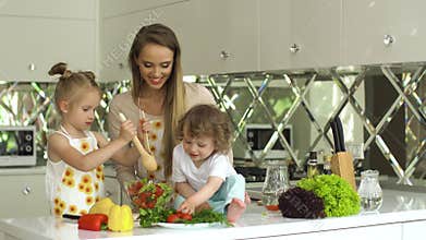 Woman With Kids Cooking Vegetables Salad At Kitchen