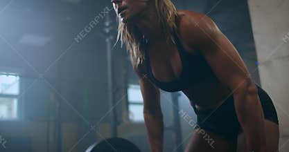 The woman athlete trains in the gym, raises the bar. Strength is power. Muscular female shirtless athlete doing deadlift