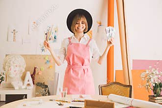 Creative girl artist or illustrator stands with cash and brushes in workshop. Concept photo about art and freelance