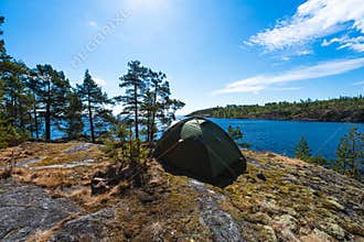 The camping tent on the top of mountain near the lake in the summer. Tourist camping tent in Karelia, Russia.