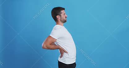 Millennial guy suffering from backache, massaging lower back