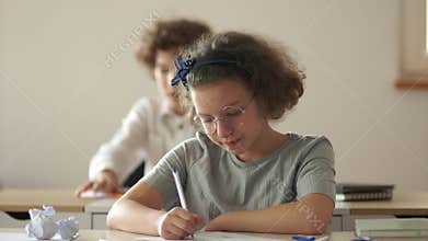 Education, elementary school, learning and people concept - group of school kids with pens and notebooks writing test in
