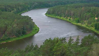 Aerial view of beautiful river Nemunas surrounded by pine forest in Lithuania. Birdseye view of nature scene on a sunny day