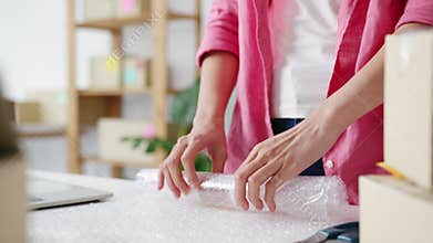 Young Asia entrepreneur businesswoman packing product in cardboard box deliver to customer, working at home office.