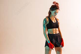 Athletic girl in stylish sportswear stands in studio isolated on beige background. Copy space. Women`s active lifestyle