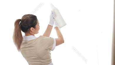 Housekeeping and cleaning concept. Pretty maid dancing in front of windows dancing with spray cleaners in hands. Joyful