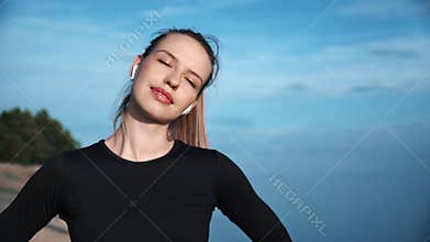 Closeup smiling fitness woman in earphones training outdoor. Shot on RED Raven 4k Cinema Camera