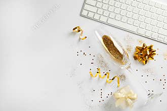 Composition of champagne glass with gold glitter, keyboard and gift box on white background. Hilarious celebration