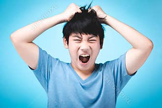 Portrait of angry asian kid on blue background