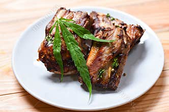 Cannabis food with bbq pork ribs grilled with herbs spices served on white plate - Roasted barbecue pork spare rib and marijuana