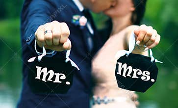 Young couple bride and groom who kiss and hold signs : Mr and Mrs