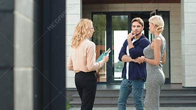 Young couple buying luxury house together. Estate agent advising house to couple