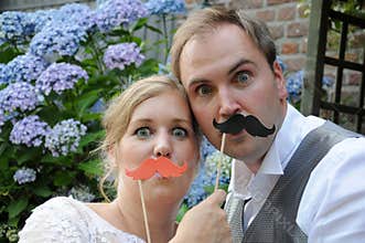 Bride and groom pose giggly in front of a photo-booth