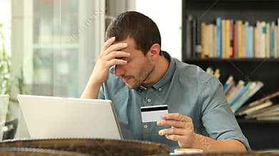Worried man buying online with credit card and laptop