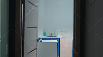 A walk in dentist`s office through corridor where young dentis works with woman patient and takes off medical mask in