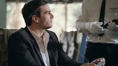 Businessman paying smartphone forrestaurant bill. Mobile phone for cafe payment