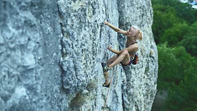 Sports woman with colored hair climbing the rock having workout in mountains.