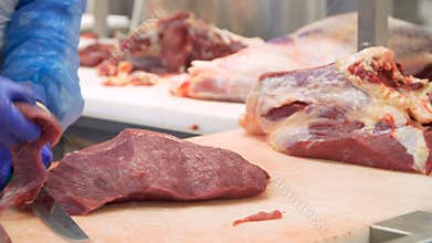 Butcher cutting beef by the conveyor belt