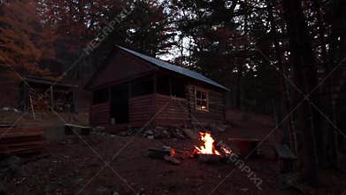 Slow Motion. Burning bonfire in the taiga at night against the background of a wooden hut. Autumn landscape