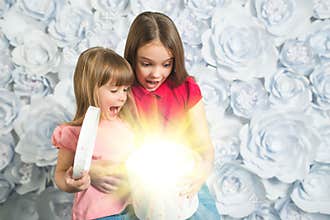 Two surprised little girls open a gift