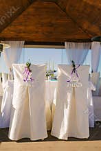 Wedding chairs in white covers of the bride and groom with the words `mr` and ` mrs ` in the gazebo