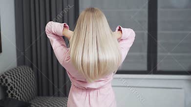 Slow motion shooting of young woman demonstrates long blonde hair