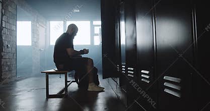 Young muscular Caucasian man putting backpack inside locker in dark gym changing room before workout slow motion.